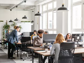 Office workers working at desk and an informal meeting