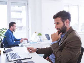 Two men at desks using PCs